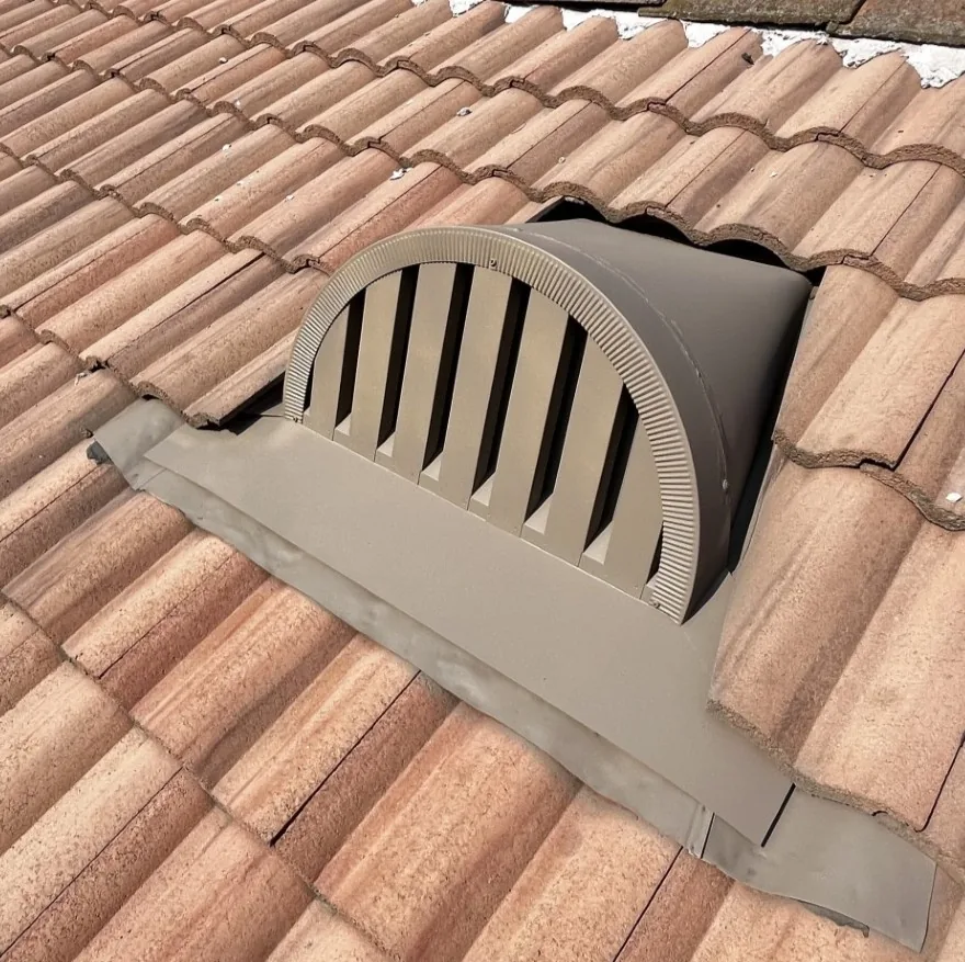 Ember-resistant dormer vent under a red tile roof