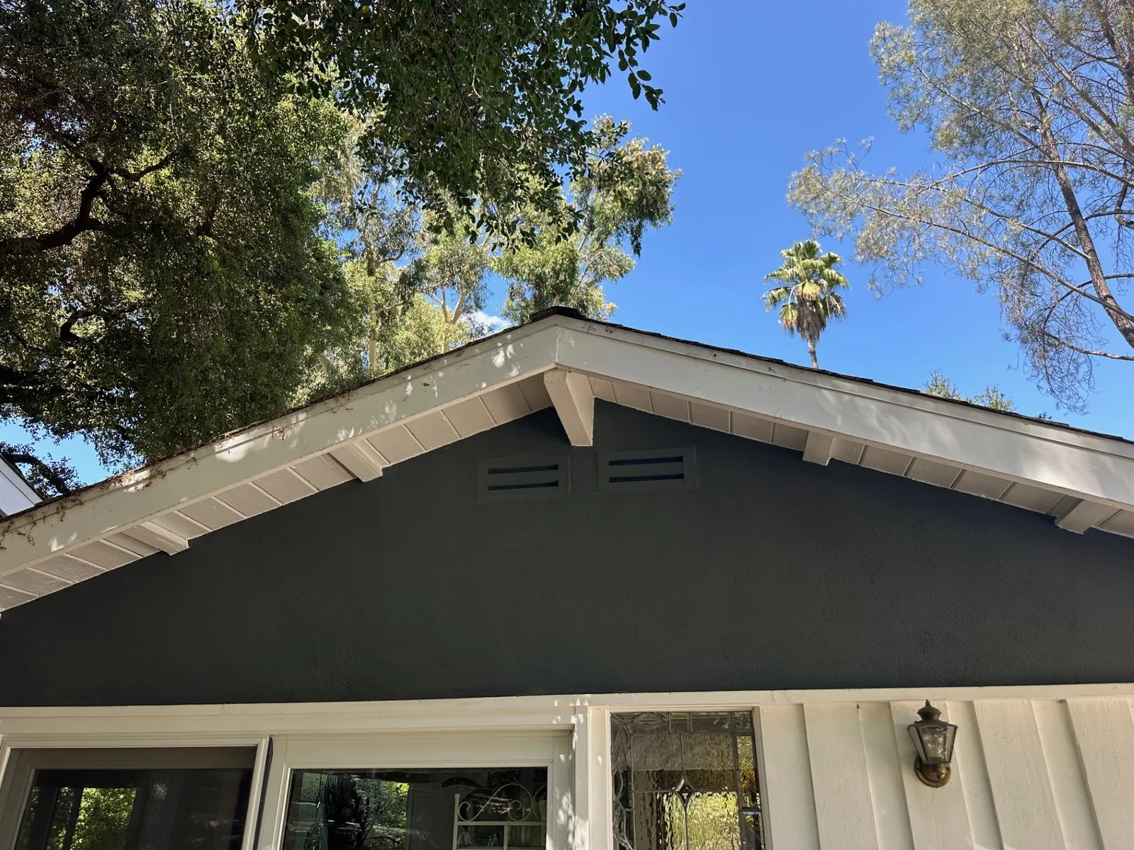 Twin ember-resistant gable vents on a dark green craftsman gable