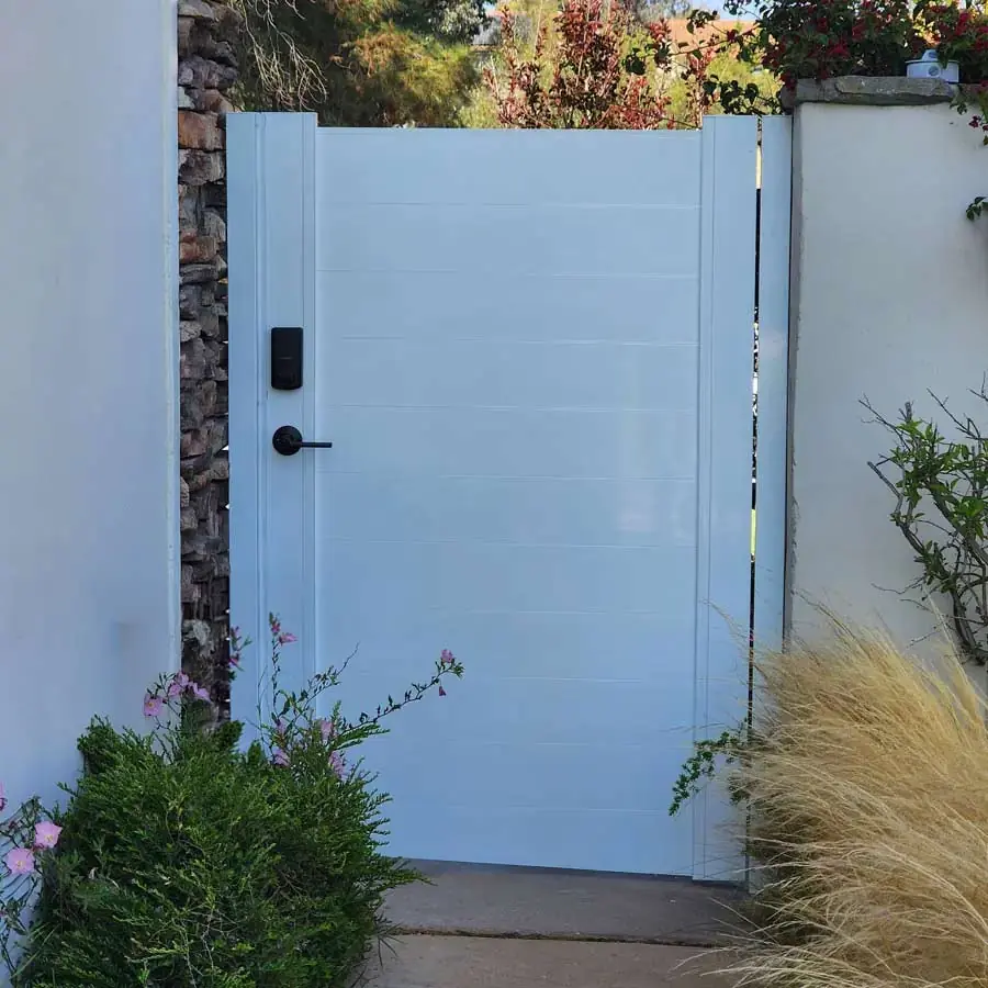 White aluminum pedestrian gate with black smart lock between stucco walls